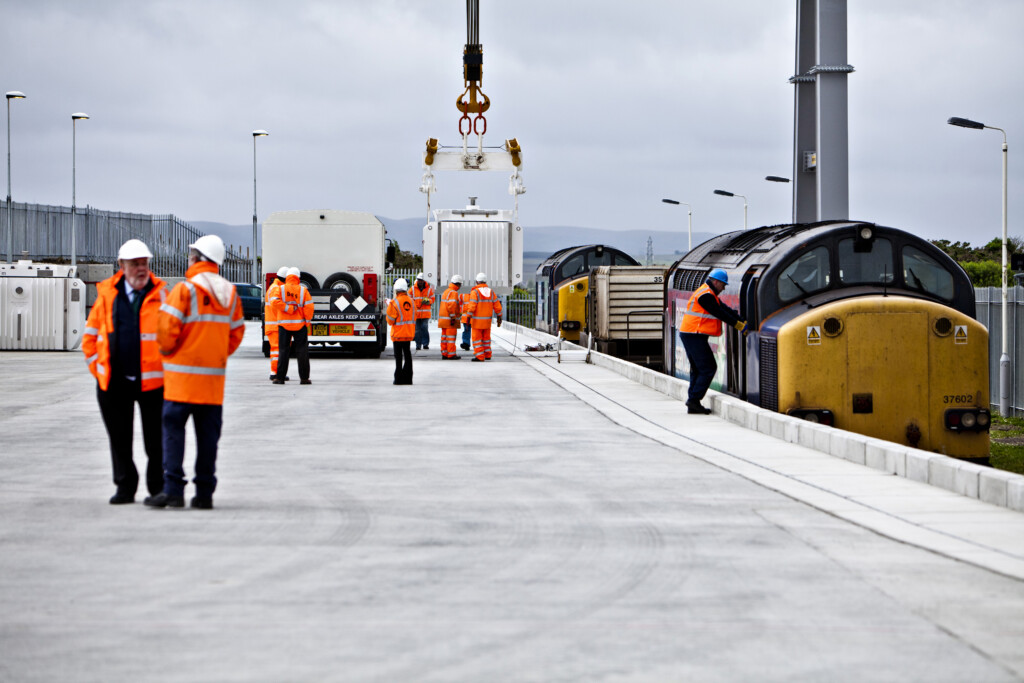 Workers in high-vis with crane unloading waste from a train